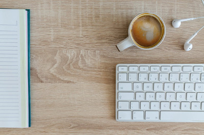 A cup of coffee on a desk with a keyboard.